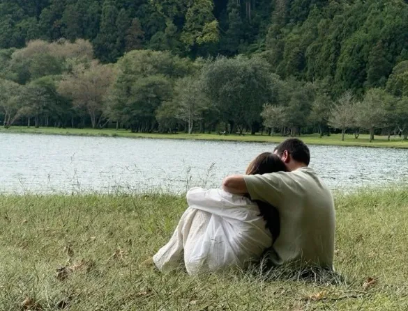 A couple resting by a lake on a work-for-accommodation summer break, recharging in the UK countryside