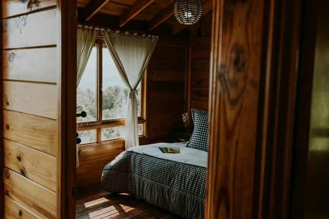 Cozy guest bedroom with wooden walls and soft light, prepared to welcome a work-for-accommodation volunteer.