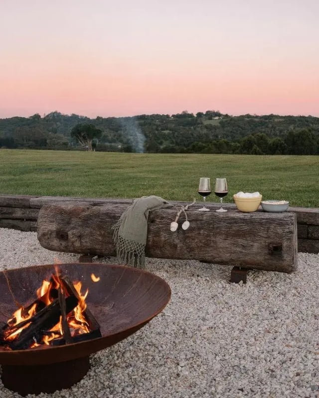 Evening fire pit with drinks overlooking rolling countryside, representing calm and alternative countryside stays UK.